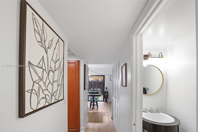 corridor with sink and light hardwood / wood-style floors