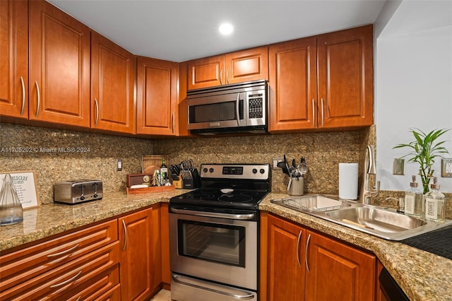 kitchen featuring light stone countertops, appliances with stainless steel finishes, backsplash, and sink