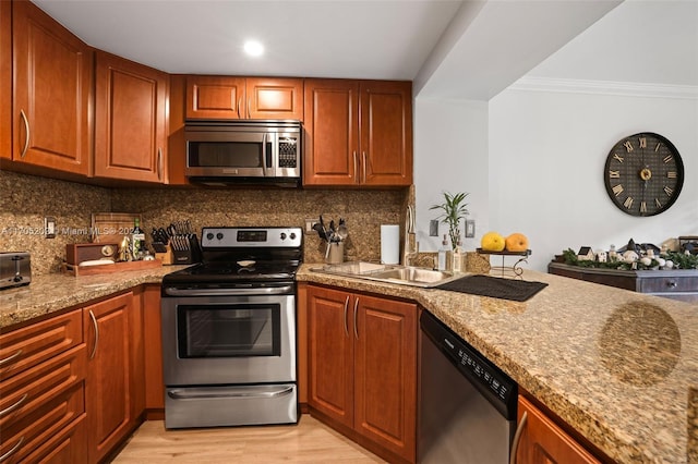 kitchen with appliances with stainless steel finishes, light wood-type flooring, ornamental molding, and backsplash