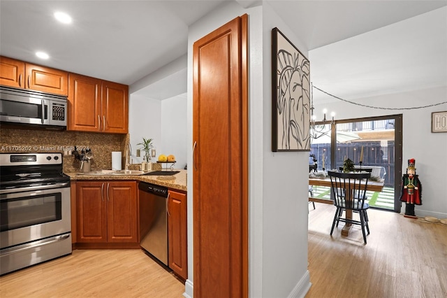 kitchen featuring tasteful backsplash, light hardwood / wood-style flooring, a chandelier, stone countertops, and appliances with stainless steel finishes