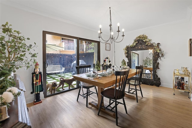 dining space with wood-type flooring, crown molding, and an inviting chandelier