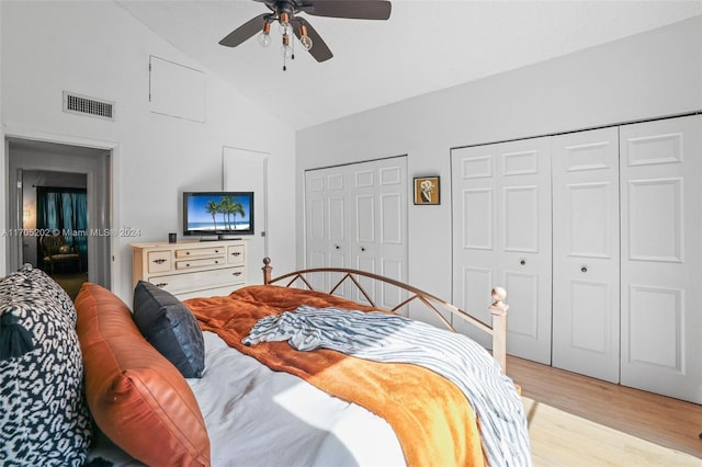 bedroom with ceiling fan, multiple closets, high vaulted ceiling, and light hardwood / wood-style flooring