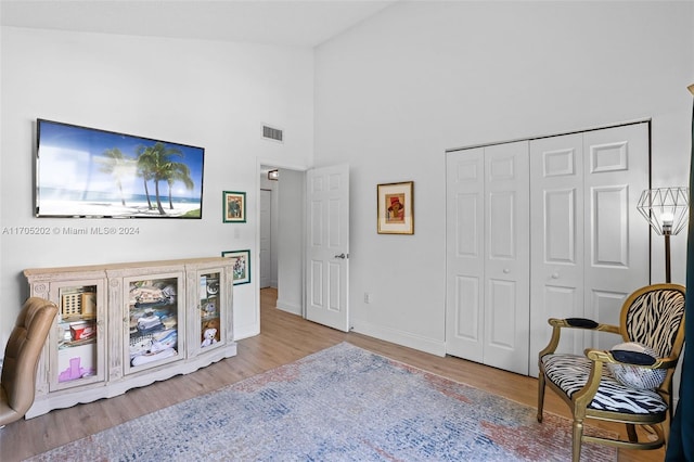 sitting room with light wood-type flooring and high vaulted ceiling