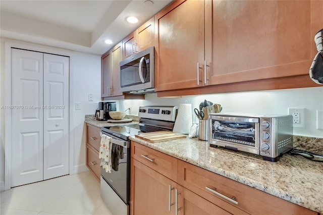 kitchen featuring light stone countertops, light tile patterned floors, and stainless steel appliances