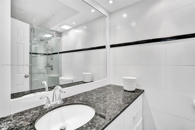 bathroom featuring vanity, a shower with shower door, tile walls, and toilet