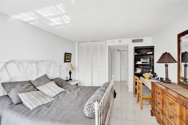 bedroom featuring light tile patterned flooring, a textured ceiling, and a closet