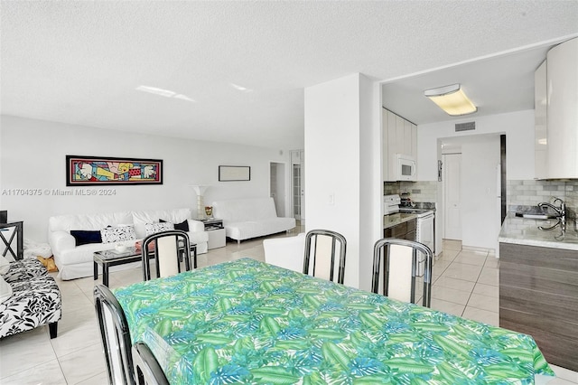 tiled dining space featuring a textured ceiling and sink