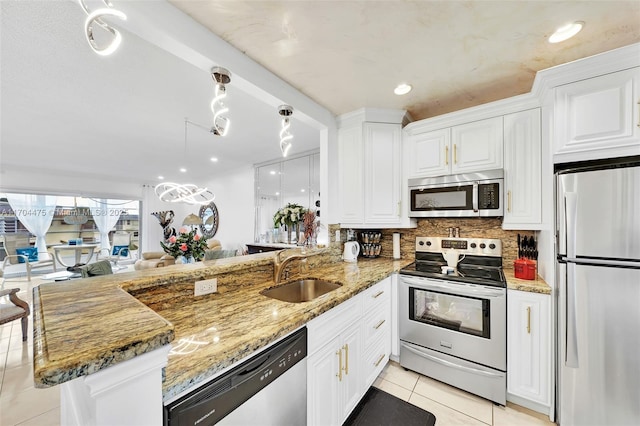 kitchen with appliances with stainless steel finishes, decorative light fixtures, white cabinetry, sink, and kitchen peninsula