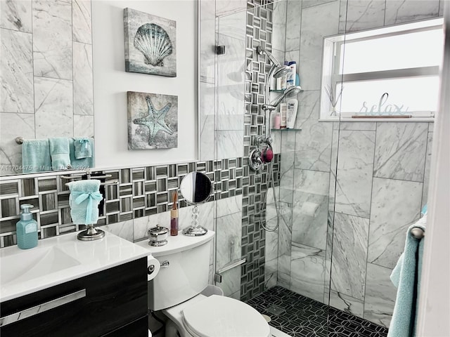 bathroom with tiled shower, vanity, toilet, and tile walls