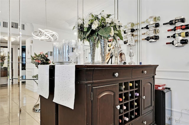 bar with dark brown cabinetry, hanging light fixtures, light tile patterned floors, and ornamental molding