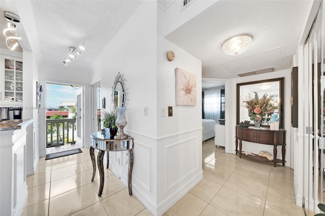 foyer entrance featuring light tile patterned floors, rail lighting, and a textured ceiling