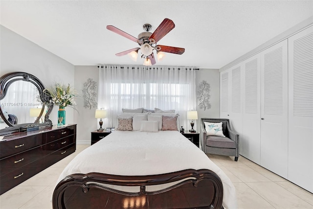 bedroom with light tile patterned flooring, ceiling fan, and a closet