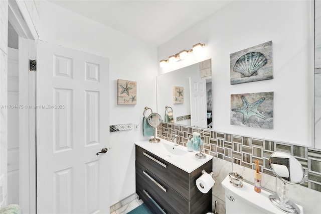 bathroom featuring tasteful backsplash, vanity, tile walls, and toilet