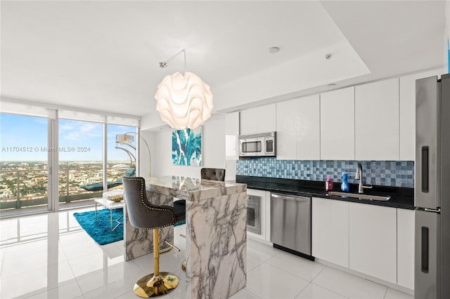 kitchen featuring a center island, backsplash, sink, white cabinetry, and stainless steel appliances