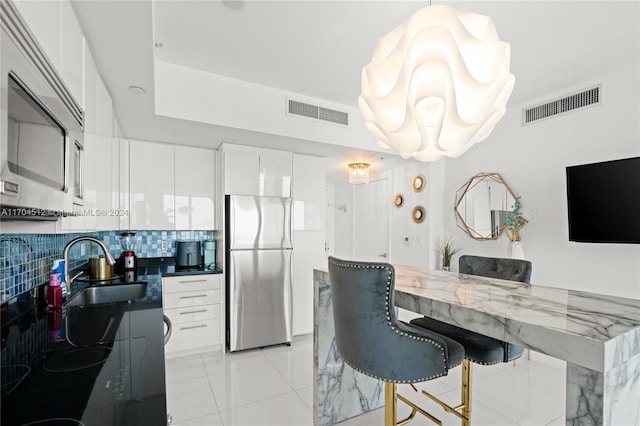 kitchen featuring white cabinets, decorative backsplash, stainless steel appliances, and sink