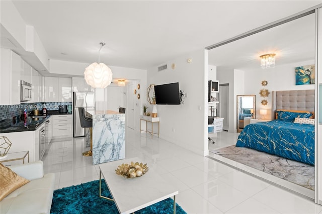 interior space with decorative light fixtures, appliances with stainless steel finishes, tasteful backsplash, a notable chandelier, and white cabinetry