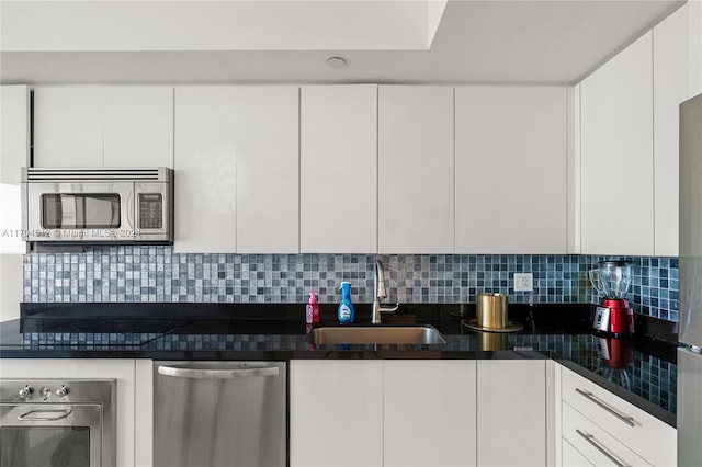 kitchen featuring white cabinets, appliances with stainless steel finishes, decorative backsplash, and sink