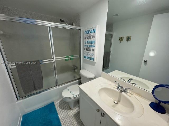 full bathroom with toilet, vanity, tile patterned floors, and enclosed tub / shower combo