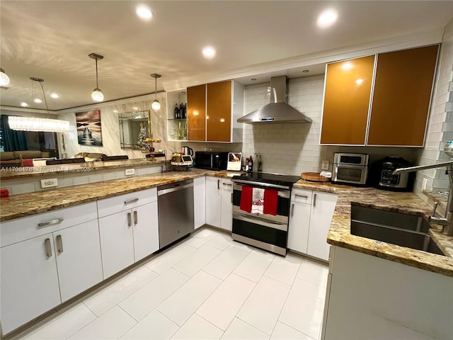 kitchen with appliances with stainless steel finishes, tasteful backsplash, hanging light fixtures, wall chimney range hood, and white cabinets