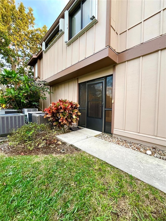 property entrance with central AC and a yard