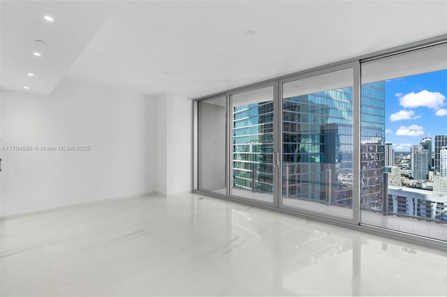 empty room featuring a view of city, recessed lighting, a wealth of natural light, and baseboards