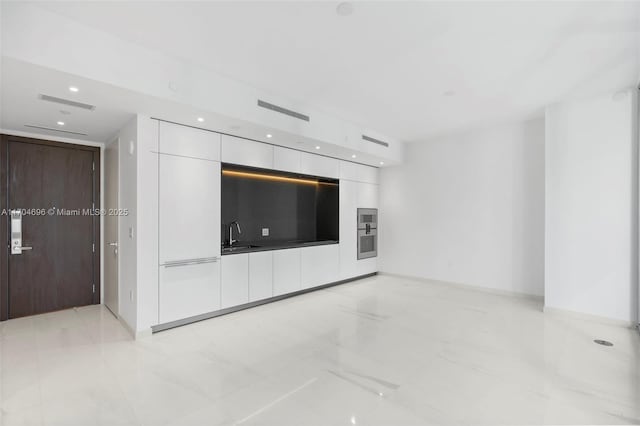 unfurnished living room featuring marble finish floor, recessed lighting, visible vents, a sink, and baseboards