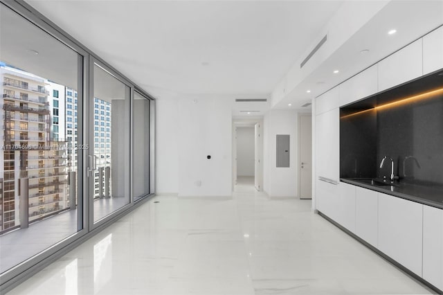 interior space featuring marble finish floor, floor to ceiling windows, a sink, electric panel, and baseboards