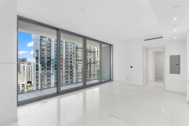 unfurnished room with a wall of windows, a view of city, electric panel, and baseboards