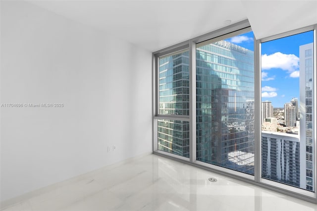 spare room featuring a view of city and a wall of windows