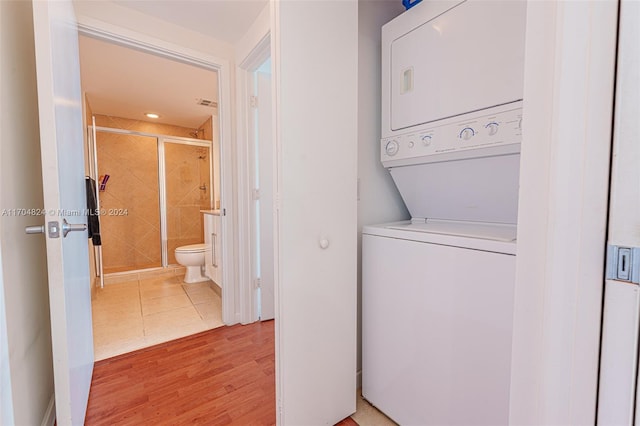 laundry area with light hardwood / wood-style flooring and stacked washer and clothes dryer