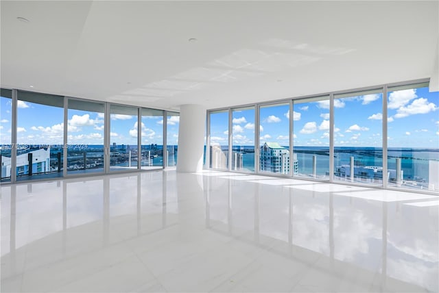 empty room featuring floor to ceiling windows, a water view, and light tile patterned floors