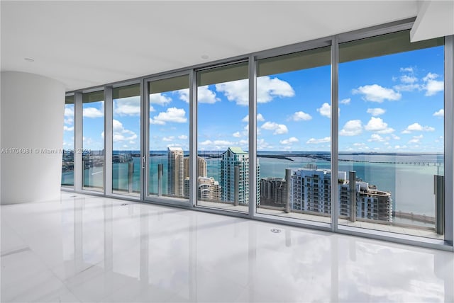 spare room featuring tile patterned flooring, floor to ceiling windows, and a water view