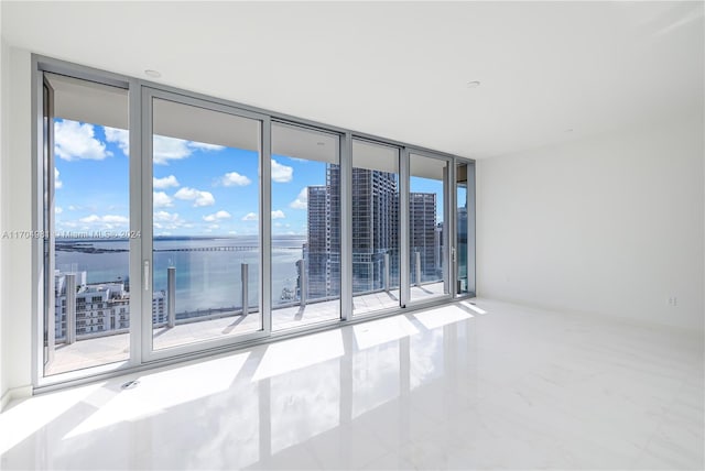 empty room featuring a water view, expansive windows, and a healthy amount of sunlight