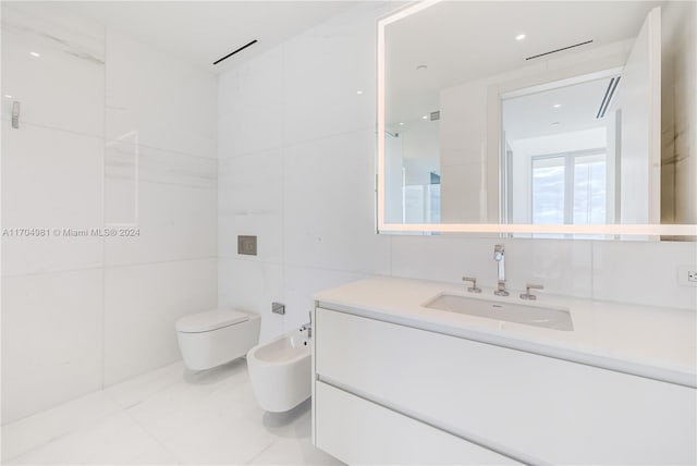 bathroom with vanity, a bidet, toilet, and tile walls