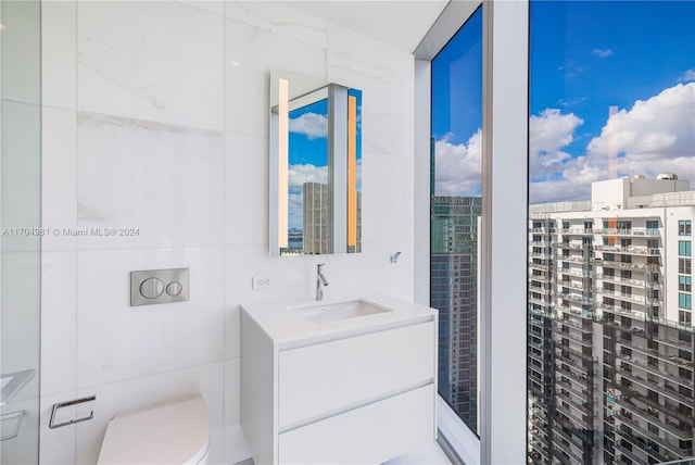 bathroom featuring vanity, toilet, and tile walls