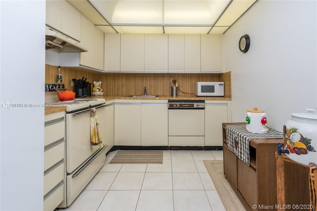 kitchen featuring light tile patterned flooring, cream cabinetry, white appliances, and sink