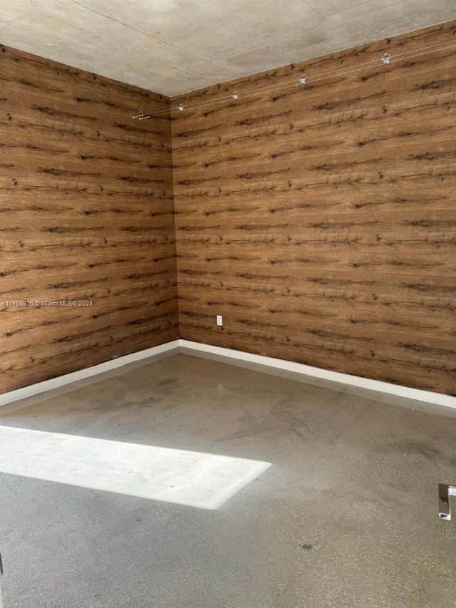 unfurnished room featuring dark colored carpet and wooden walls