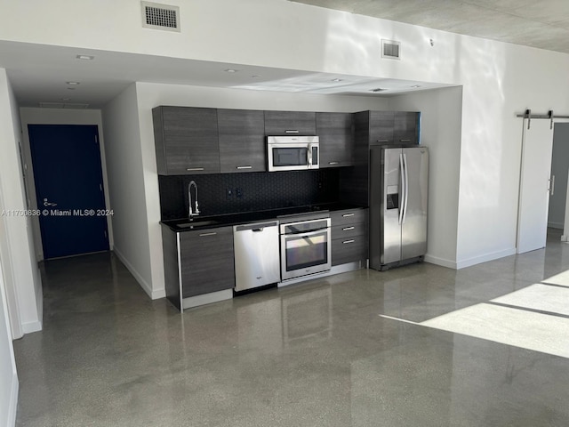 kitchen featuring a barn door, sink, backsplash, and appliances with stainless steel finishes