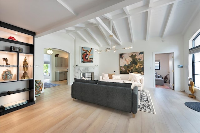 living room featuring a high end fireplace, lofted ceiling with beams, and light wood-type flooring