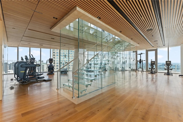 exercise room featuring hardwood / wood-style floors, a water view, and expansive windows