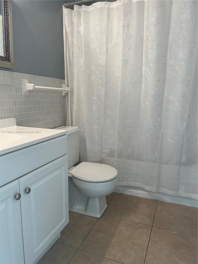 bathroom with tile patterned floors, vanity, tile walls, and toilet