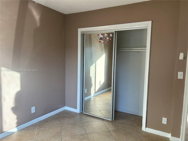 unfurnished bedroom featuring a closet and light tile patterned floors