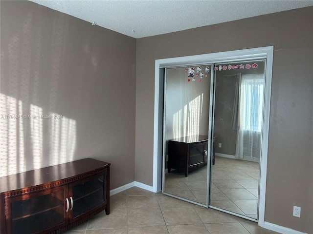 interior space featuring a closet, light tile patterned flooring, and a textured ceiling