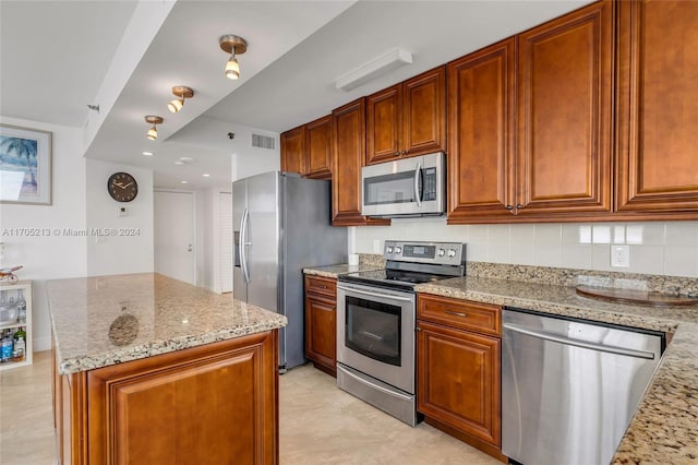 kitchen with appliances with stainless steel finishes, tasteful backsplash, and light stone counters