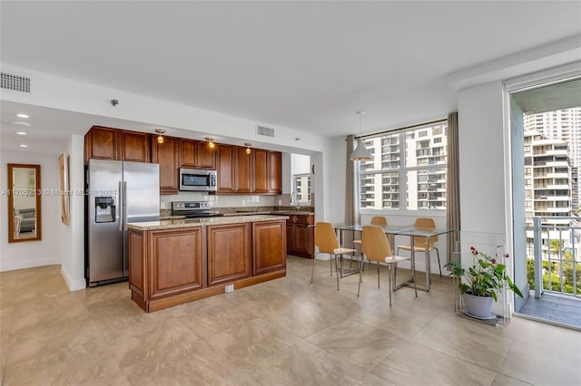 kitchen featuring plenty of natural light, light stone countertops, stainless steel appliances, and hanging light fixtures