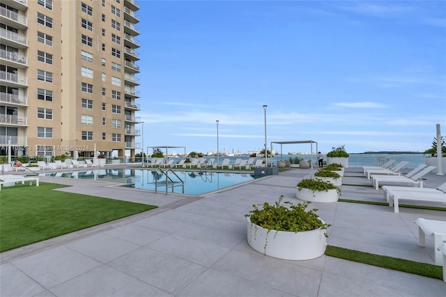 view of pool featuring a patio area, a yard, and a water view