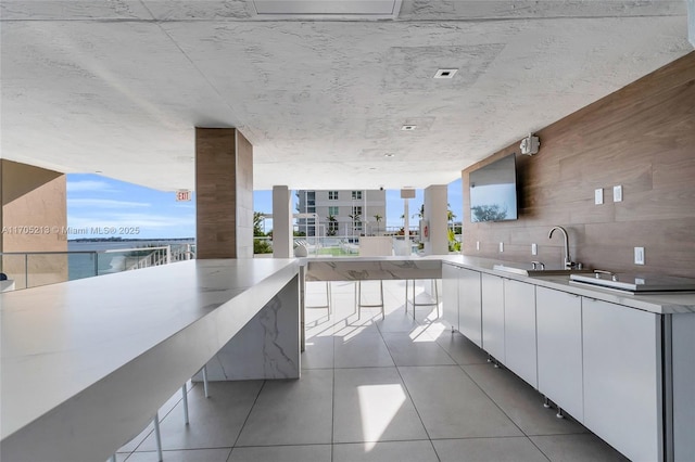 kitchen with floor to ceiling windows, light tile patterned floors, backsplash, white cabinets, and modern cabinets