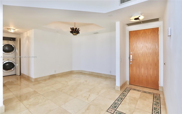 foyer entrance with visible vents, baseboards, and stacked washer and dryer