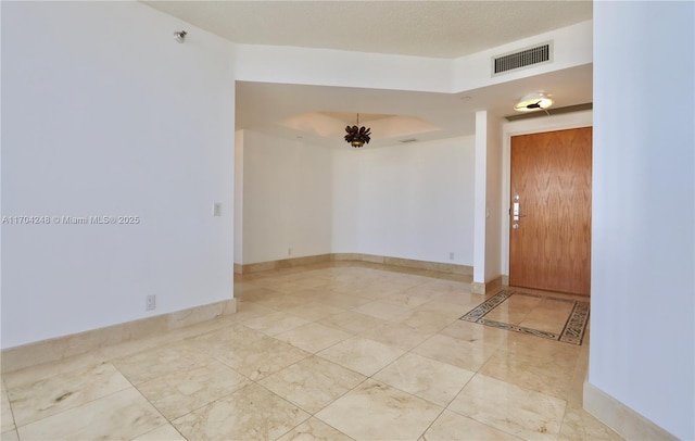 unfurnished room with baseboards, visible vents, and a chandelier