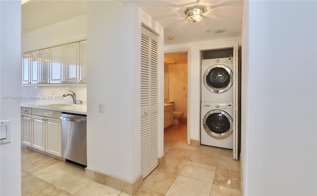 laundry room featuring a sink, stacked washer and clothes dryer, and laundry area